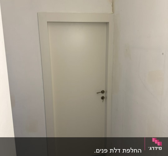 דלת לבנה עם ידית מתכת על קיר לבן